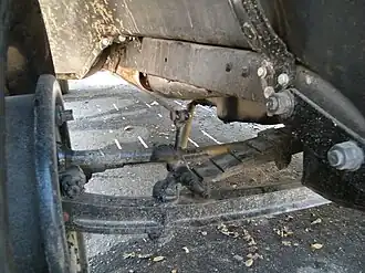 Передний мост на поперечно расположенной полуэллиптической рессоре, видна тяга к тормозному механизму