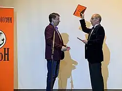 На завершающем вечере журнала поэзии «Арион» в Доме русского зарубежья Алексей Алёхин вручает Евгению Коновалову диплом лауреата.