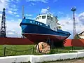 Буксир «Шторм» с ледокольным носом как памятник перед ограждением порта