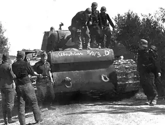 Немецкие военнослужащие осматривают «расейняйский КВ», 25 июня 1941 года. Как указывает М. В. Коломиец, надпись на корпусе танка свидетельствует о том, что он был уничтожен расчётом орудия D 2-й батареи 1-го дивизиона 3-го зенитного полка