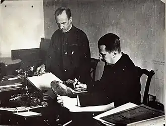 В кабинете учёного секретаря Эрмитажа. М. Д. Философов (сидит) и делопроизводитель Б. И. Игнатьев. На заднем плане — диван Пушкина.Конец 1920-х годов