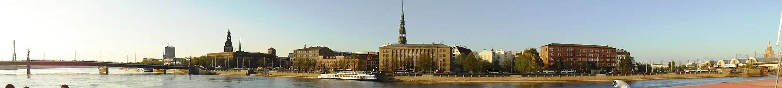 Набережная 11 Ноября. Слева — Каменный мост через Даугаву, правее него шпили Домского собора и церкви Св. Екаба. Здание в центре — Государственная земельная служба Латвии, за ней — шпиль церкви Св. Петра. Справа — Центральный рынок и здание Академии наук Латвии