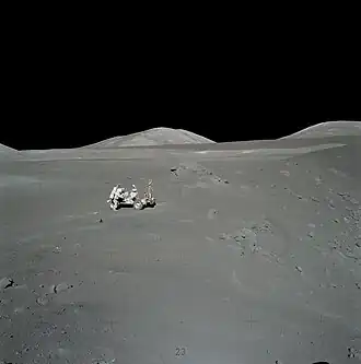 Шмитт у «Ровера» на Station 4. Между «Ровером» и валуном видно пятно оранжевого грунта. Справа — кратер Шорти