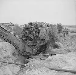 Танк «Черчилль» переносит фашины через ров, уже заполненный фашинами.