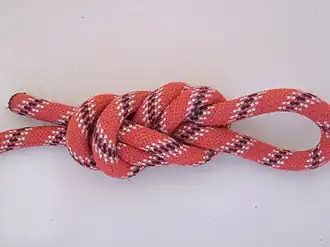 3. Затянуть, одновременно потянув за петлю и сложенные вместе ходовой и коренной концы верёвки; завязать контрольный узел ходовым концом верёвки вокруг коренного.