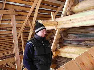 Александр Попов на лесах около реставрируемой им церкви Ризоположения из села Бородава (справа). На заднем плане слева и сверху — конструкции временного технологического павильона