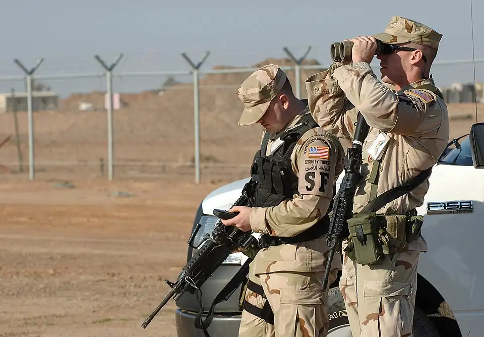 Технический сержант ВВС США Майкл Мур (Michael Moore) и старший рядовой Талиесин Фортмюллер (Taliesin Fortmuller) используют приемник глобальной системы позиционирования и бинокль для точного определения и идентификации точки удара и любых возможных неразорвавшихся боеприпасов после атаки с закрытых огневых позиций 19 февраля 2007 года по авиабазе Балад в Ираке. (Фотография ВВС США, сделанная штаб-сержантом Майклом Р. Хольцвортом).