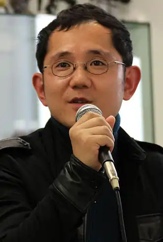 Снимок Сю Такуми с микрофоном в руках