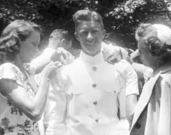 Jimmy Carter similing towards the camera, while Rosalynn Smith and his mother are fixing his Naval Academy uniform
