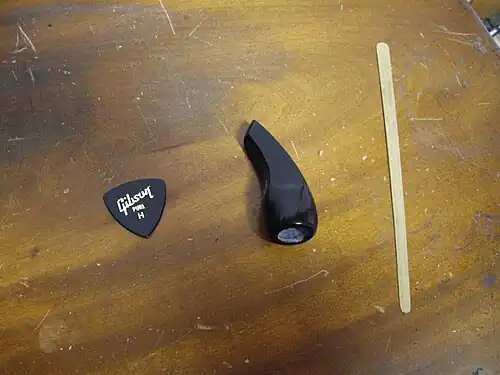 Плектры для сансина: коготь (в центре) и палочка (справа)