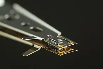 Макрофото магнитной головки, снизу — зеркальное отражение от поверхности магнитного диска