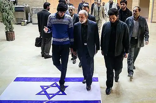 Хоссейн Шариатмадари, редактор иранской газеты «Кайхан», наступает на израильский флаг в Технологическом университете имени Амира Кабира (2015)