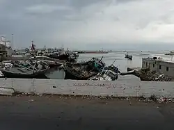 Новый порт Мукалла. Слева на фото цистерны (танки) цементной компании «RAYSUT», лагом ошвартован цементовоз (судно) «Olympic Carrier» (серый корпус, белая надстройка и красная труба) и много рыболовных судов.