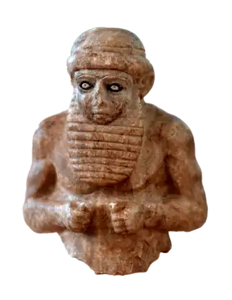 Верхняя часть туловища серой алебастровой статуэтки жреца. Найдена внутри глиняного сосуда в древнем городе Урук археологической экспедицией из немецкого Восточного общества в 1929—1930 годах. Вероятно, она была захоронена после того, как её разбили. Высота составляет около 21 см. Экспонируется в Иракском музее в Багдаде