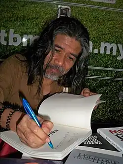 Пьян Хабиб подписывает свою книгу стихов во время поэтических чтений литературной организации «Пена» 7 июля 2017 года в Куала-Лумпуре