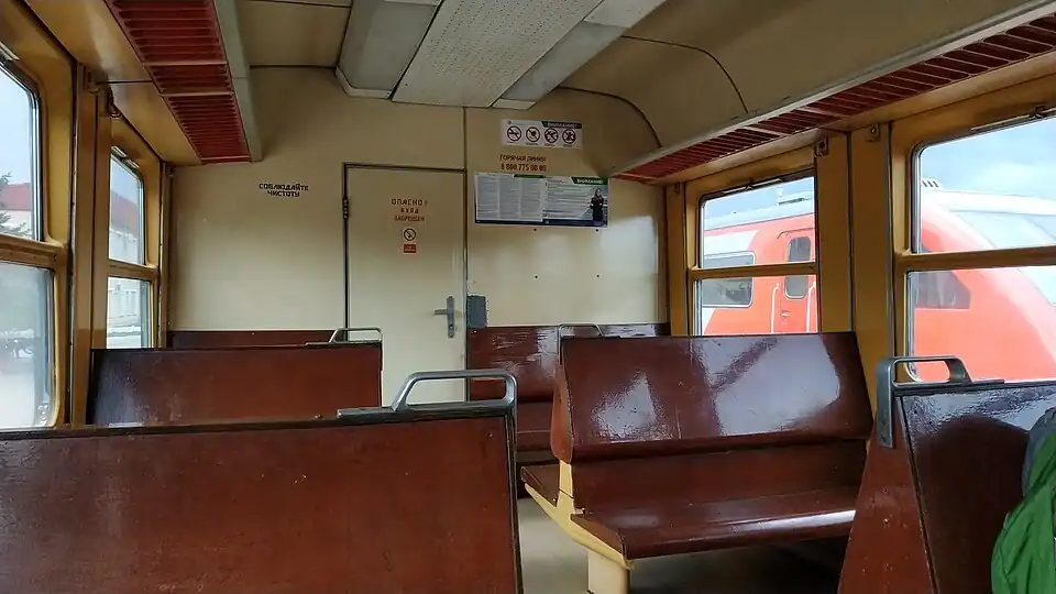 Пассажирский салон вагона АЧ2 с жёсткими сиденьями без обивки, вид в сторону машинного отделения