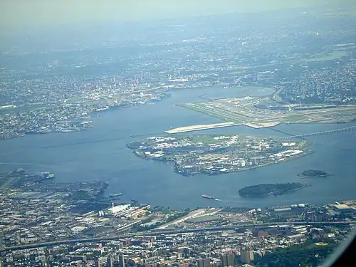 Общий вид. На переднем плане видны два поросших лесом острова: Норт-Бротер (покрупнее) и Саут-Бротер (помельче). За островом Райкерс виден аэропорт Ла-Гуардия, справа от острова — мост Острова Райкерс