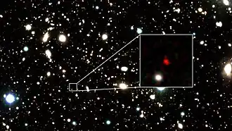 Изображение HD1, кандидата в самые удалённые галактики из известных на данный момент (13,5 млрд световых лет от Земли), созданное на основе данных телескопа VISTA[англ.]. Красный объект в центре увеличенной области — HD1