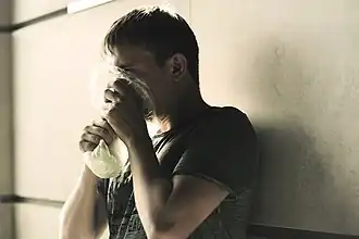 Токсикоман, нюхающий клей из пакета.