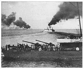 На переднем плане — кормовые орудия ЭМ «Керчь», на заднем плане — линкор «Воля».