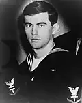 Head and shoulders of a young white man wearing a dark sailor suit with an eagle patch on the upper sleeve.